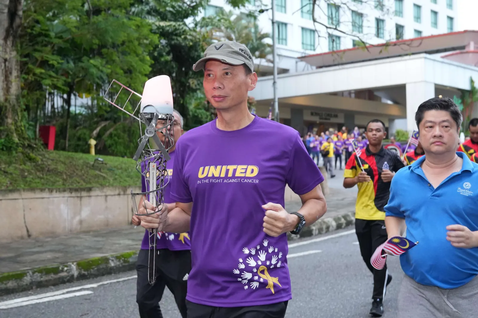 Torch relayer in a purple UNITED shirt carrying the Journey of Hope torch