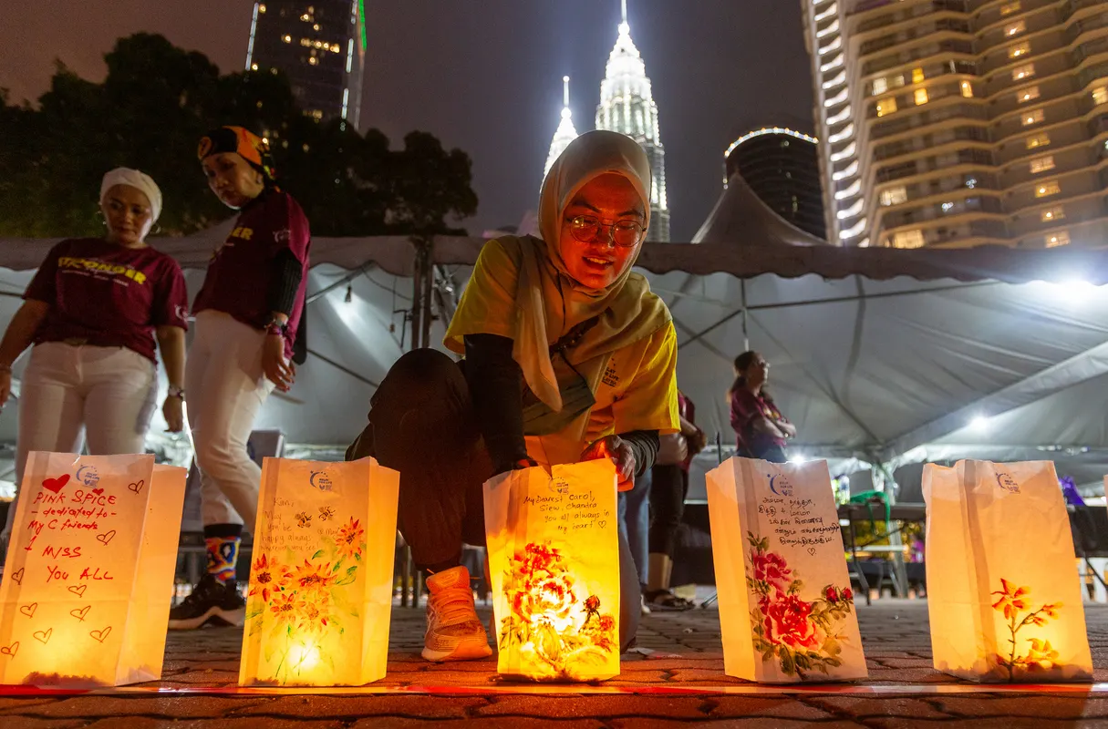 Luminaria bags glowing at night with the city skyline behind